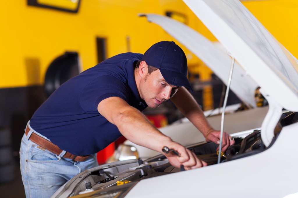 Auto mechanic repairing a white car