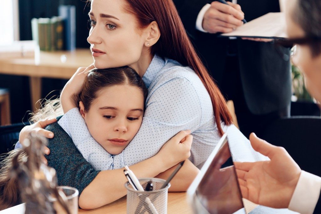 Little girl hugging mom with lawyer