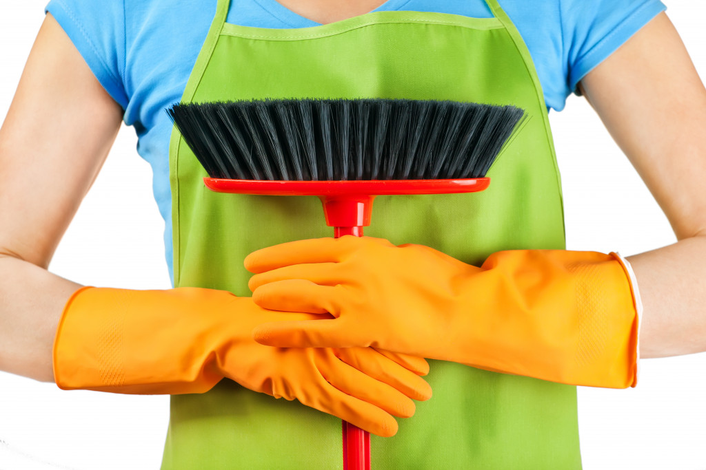 woman holding a cleaning brush with yellow rubber gloves on