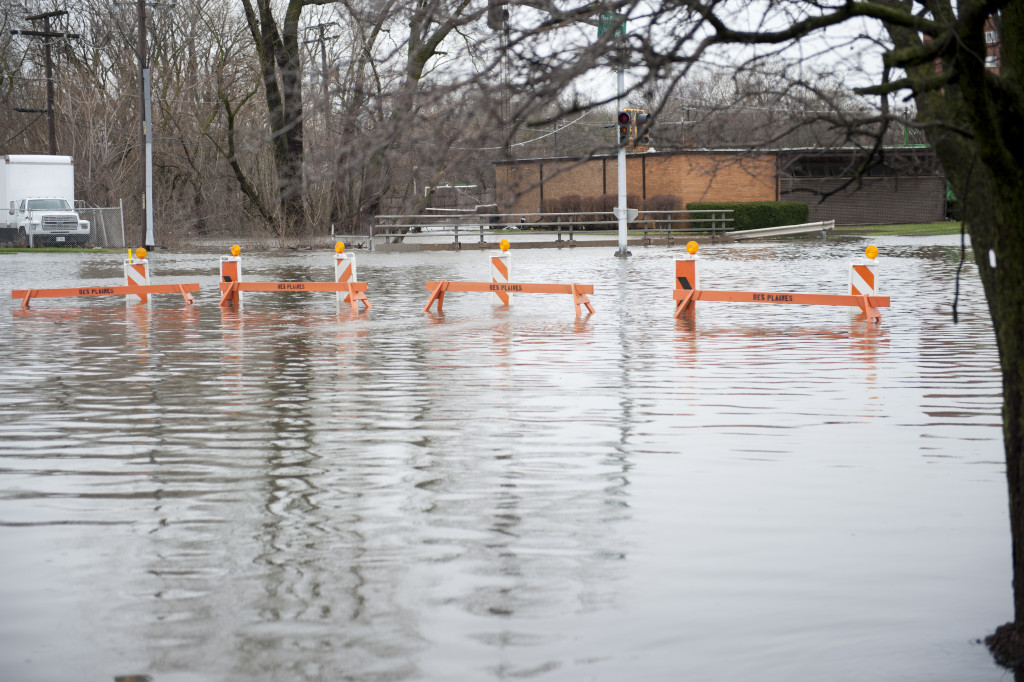 Flooded transportation sign with road barriers on a cloudy day