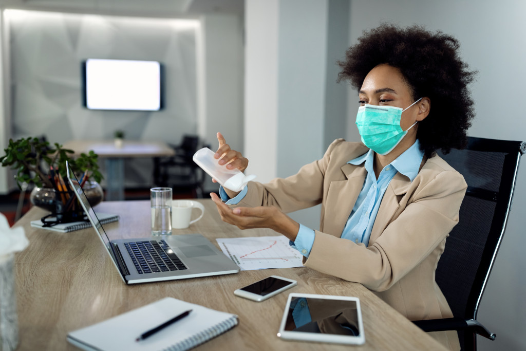 woman applying hand sanitizer wearing facemask