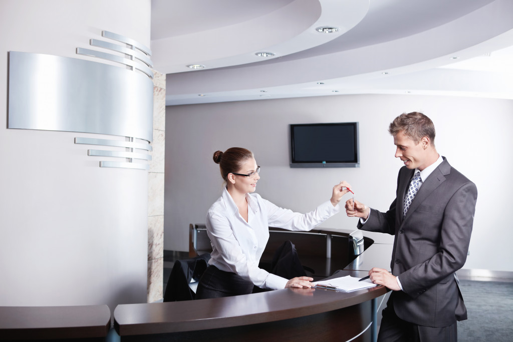 woman handing a key to the customer in a hotel reception