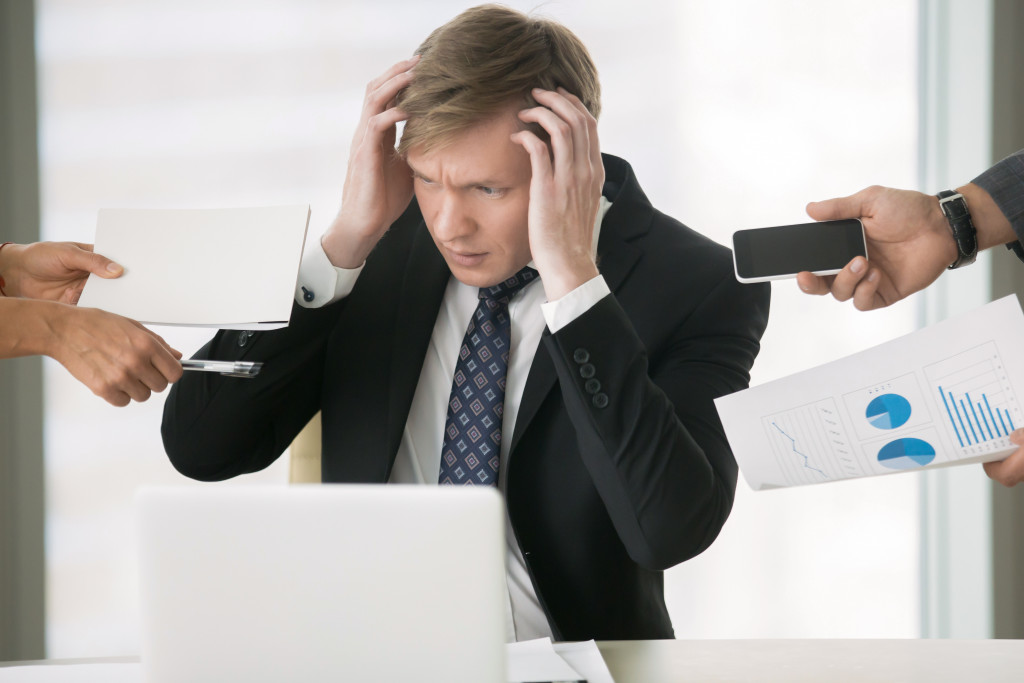 man being overwhelmed with responsibilities in the office