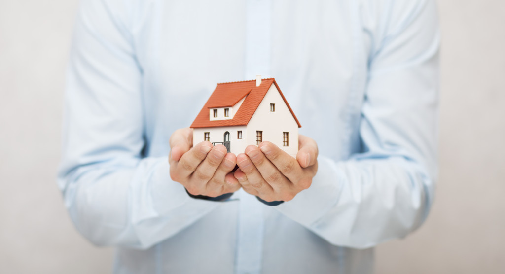 a person holding a house figurine