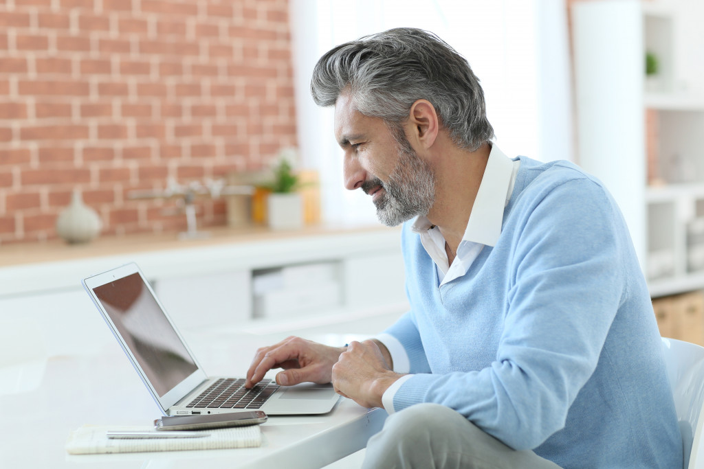 Trendy mature man working from home with laptop