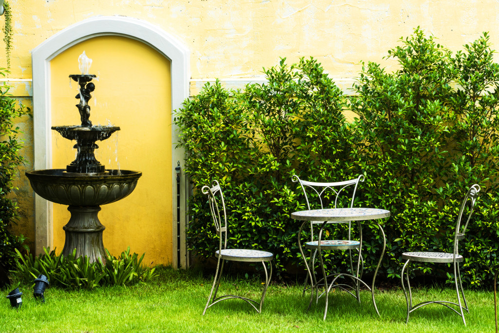 an outdoor dining table with chairs and water features and greens