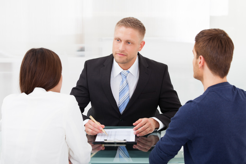 Rear view of young couple consulting financial advisor at office desk