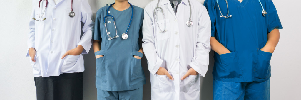 Four medical professionals standing side by side with their hands in their pockets