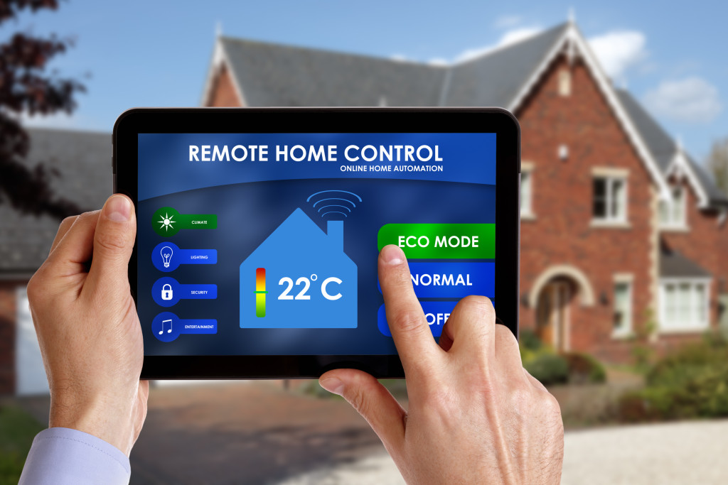 a man holding a smart home controller in front of a house