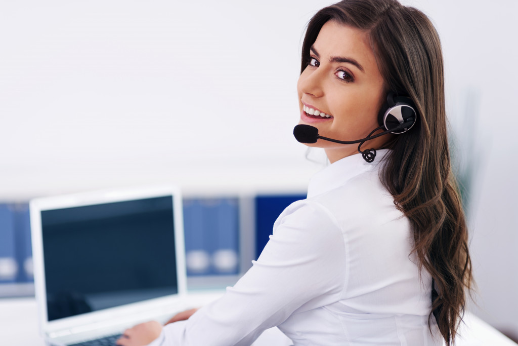 a woman using a laptop while wearing headphones