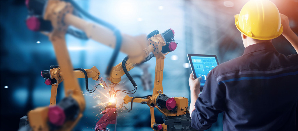 Worker monitors the performance of an automated machine in manufacturing