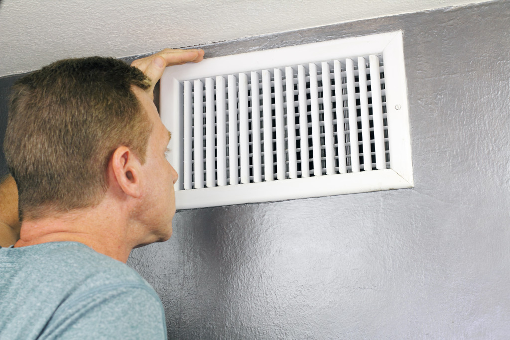 A man checking the heating vents