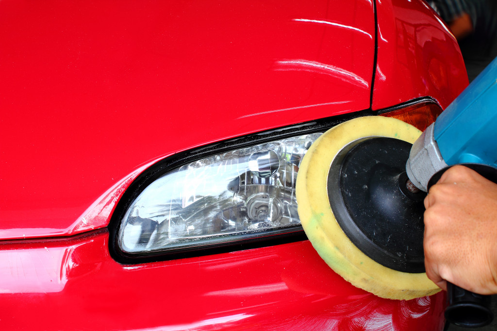 A person buffing and polishing a red luxury car