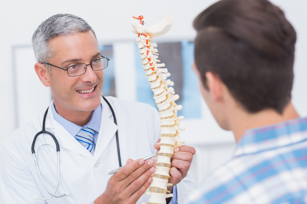 Doctor showing anatomical spine to his patient in medical office