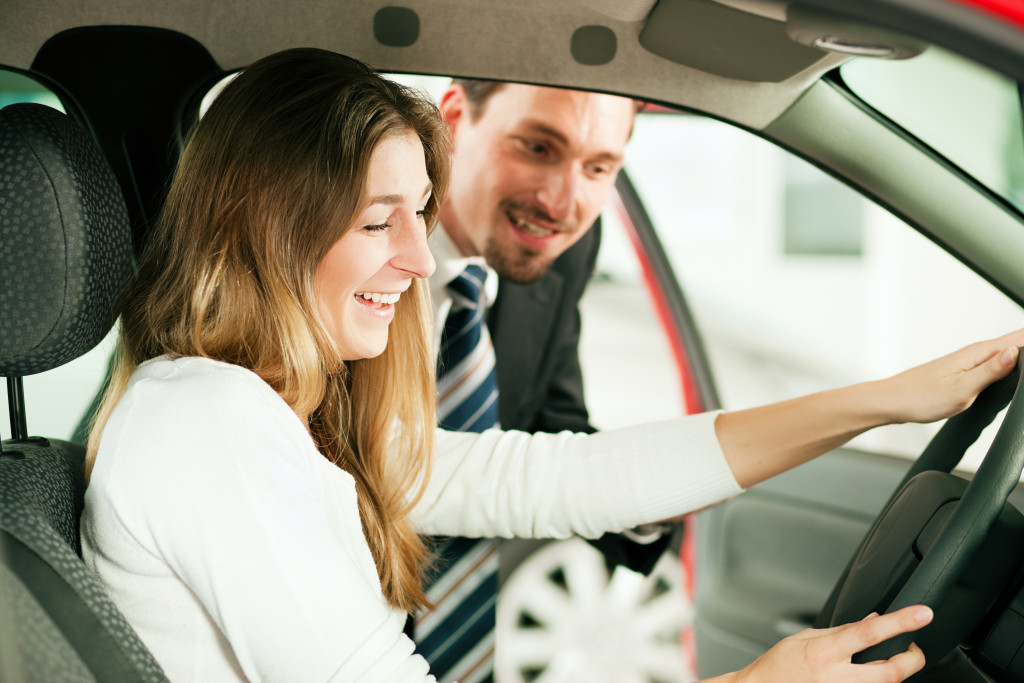 a car salesman helping a female customer look at a car