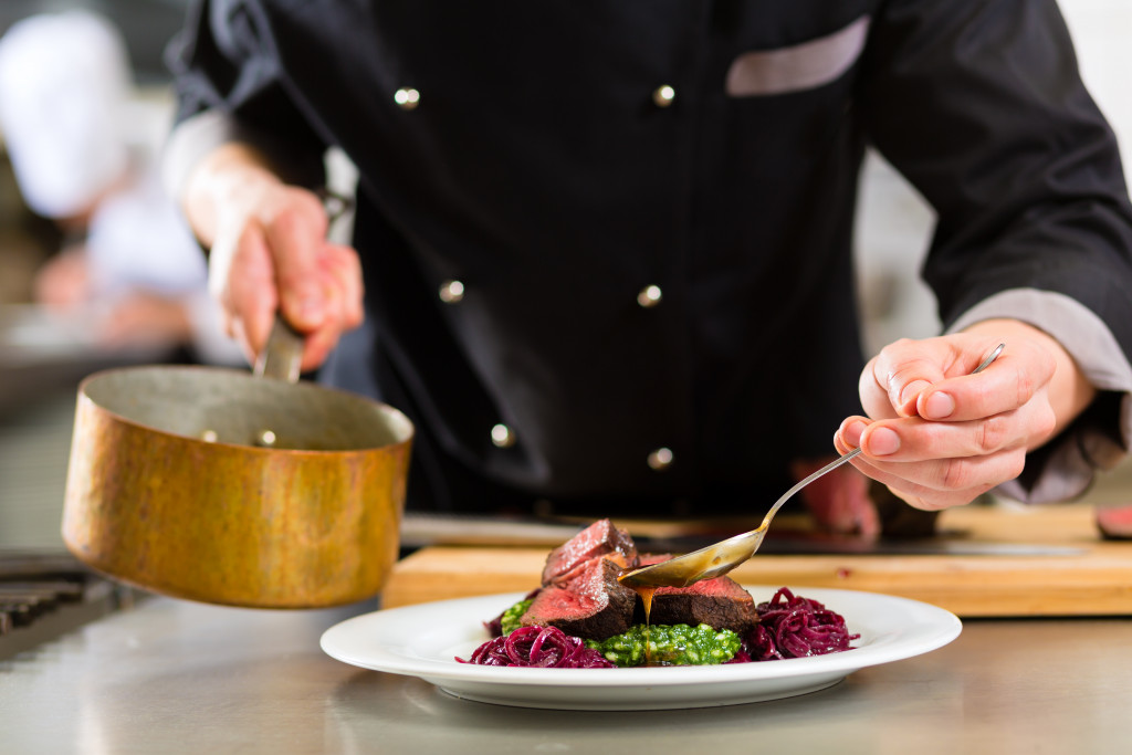 chef in a restaurant or hotel pouring sauce in meal plating arrangement