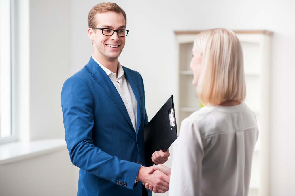 skillful male realtor and his customer are shaking hands they made a deal