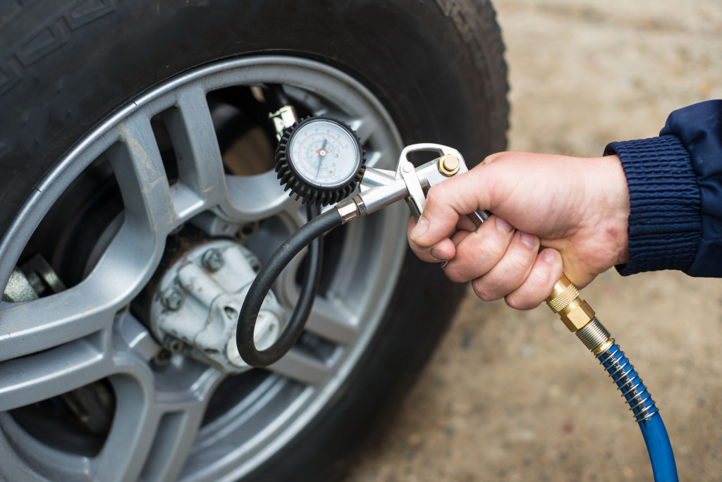 A hand adding air pressure to a car's tire