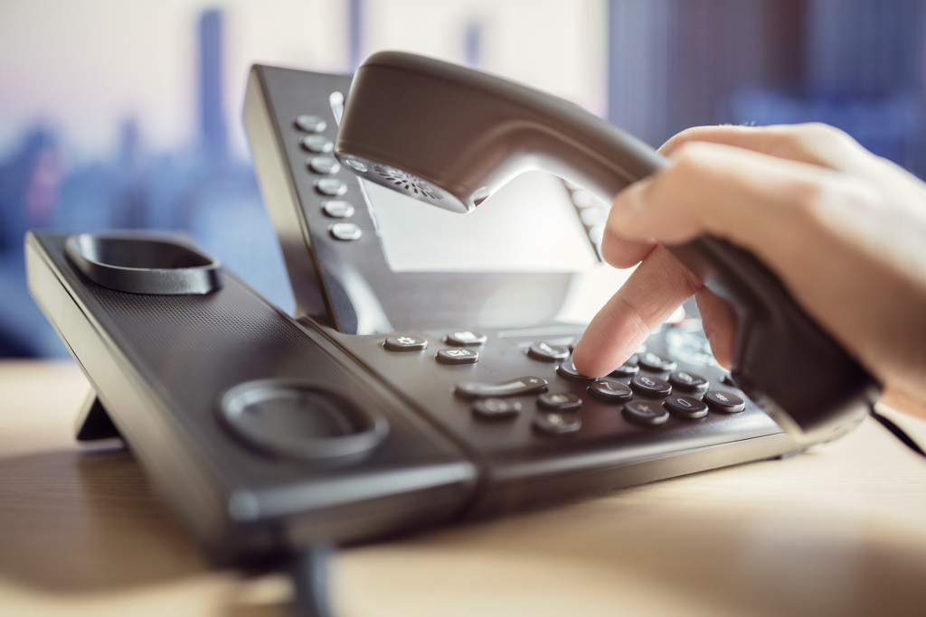 A hand using a telephone to contact customer service