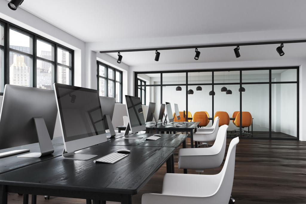 Office table with computers and chairs around it.