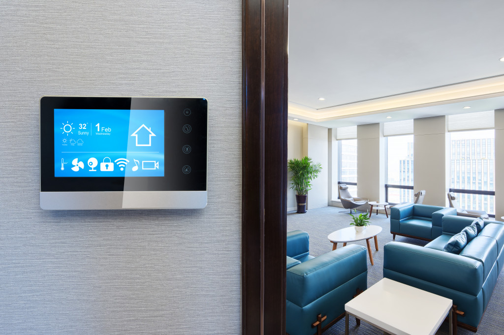 A smart thermostat installed in the wall of a house close to the living room.