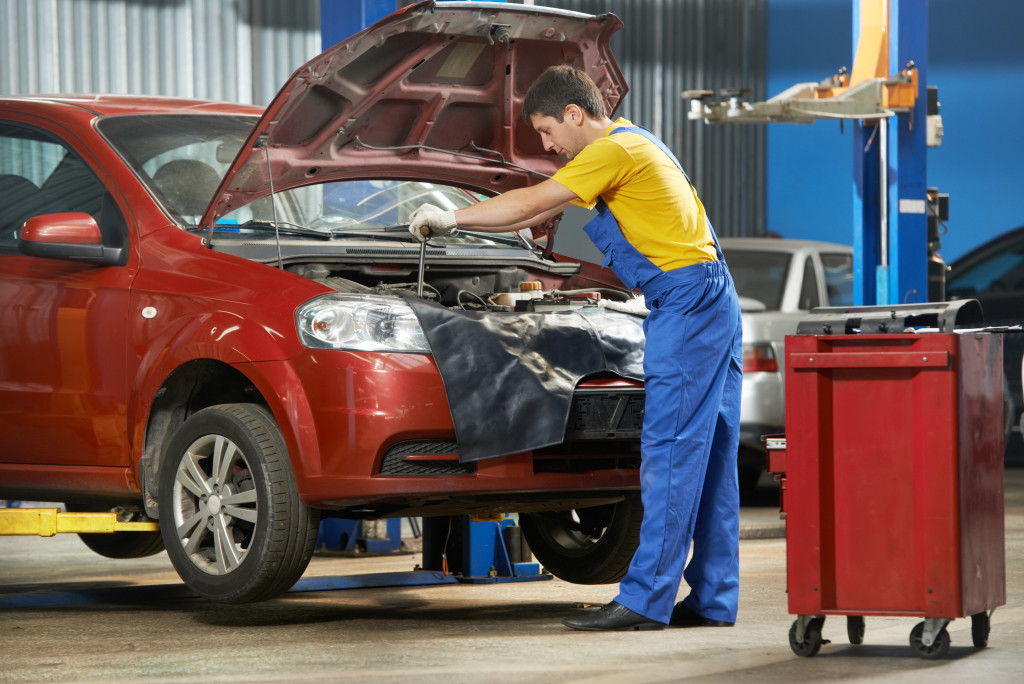 Mechanic checking the engine of a car in an auto shop.