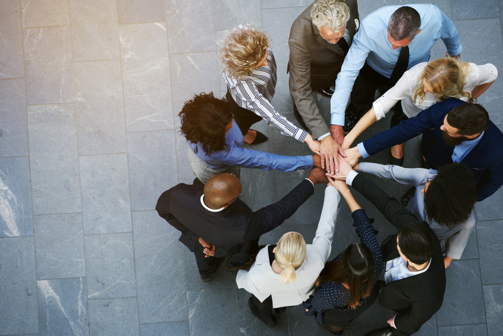 employees joining hands together outside the office