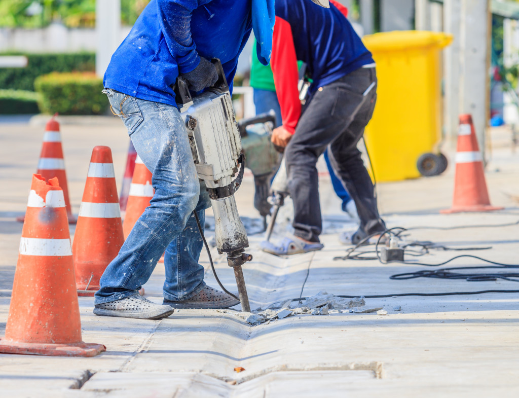 Construction workers using jackhammers to break concrete ground