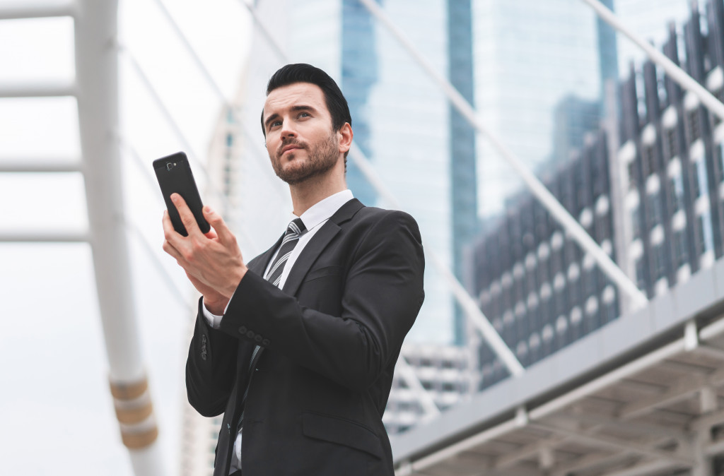 Young male executive holding a smartphone in an office.