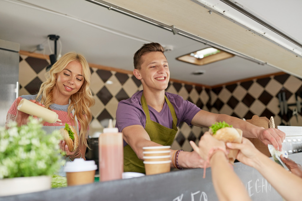 man and woman serving inside a food truck