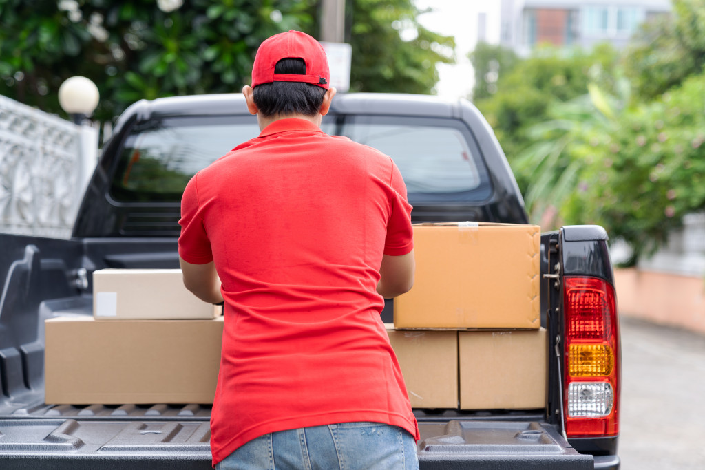 Asian delivery man wearing red uniform and red hat moving and transfer parcel boxes