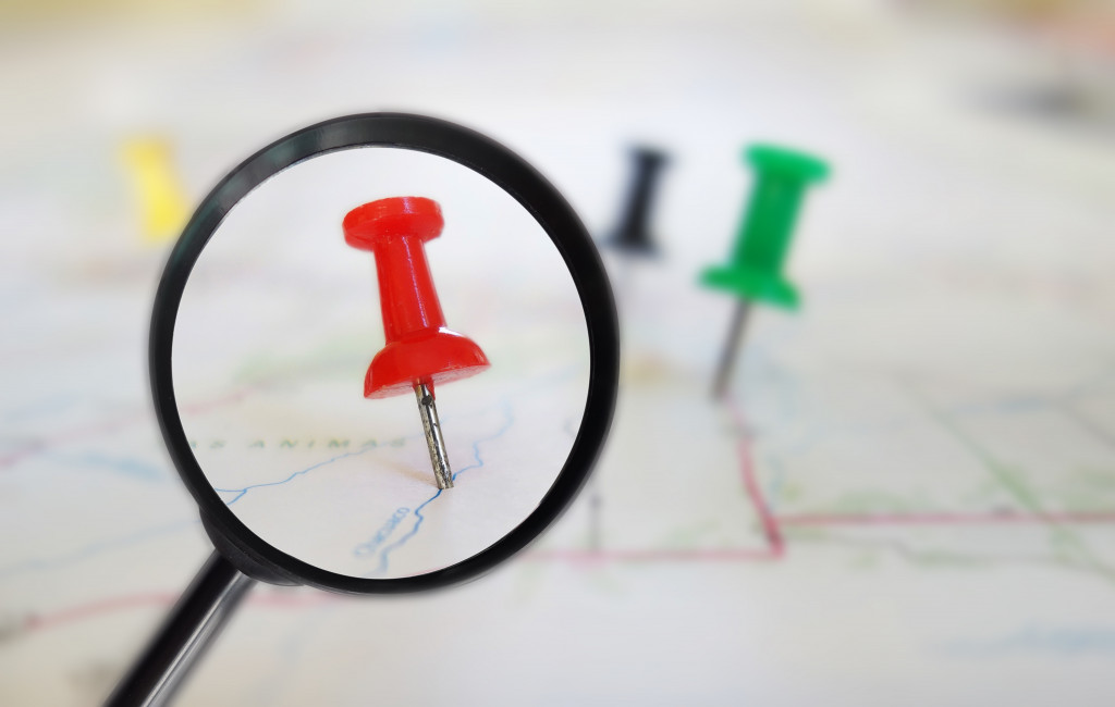 red pin under a small magnifying glass on a map