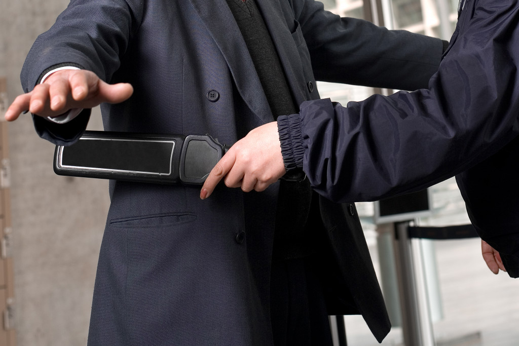 security guard scanning a male in suit before entering premises