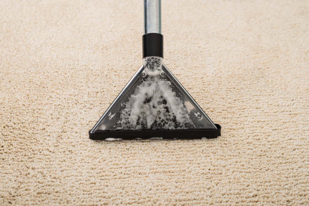 A vacuum cleaner sucking foamy water from a carpet