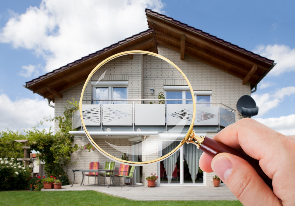 person hand with magnifying glass over home