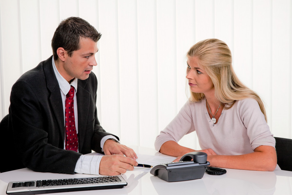 man in business suit explaining to young woman