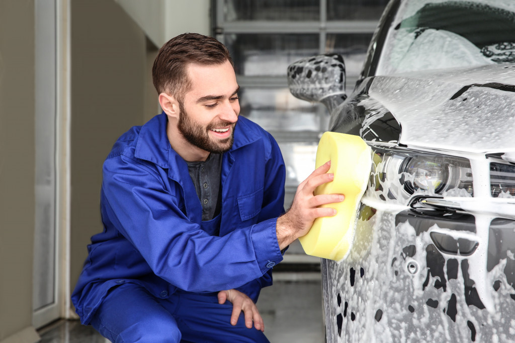 man smiling while washing the car