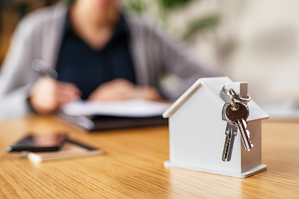 woman signing documents with a house model on front