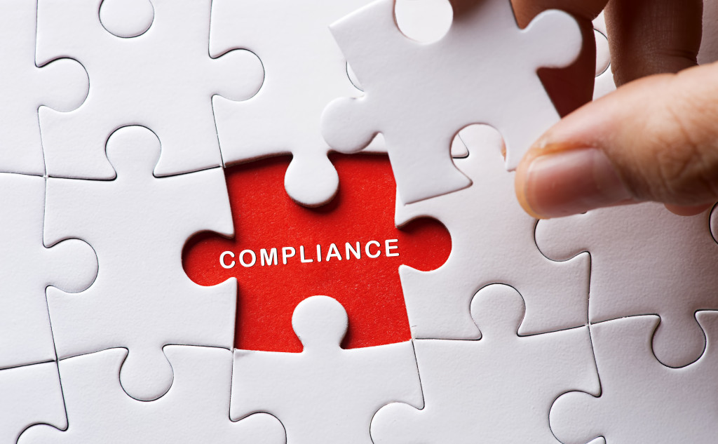 The word Compliance in the red empty space of a white jigsaw puzzle