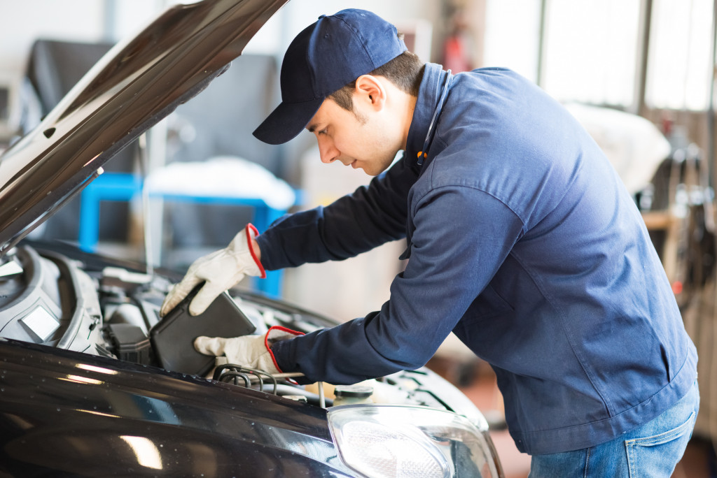 auto mechanic putting oil in car