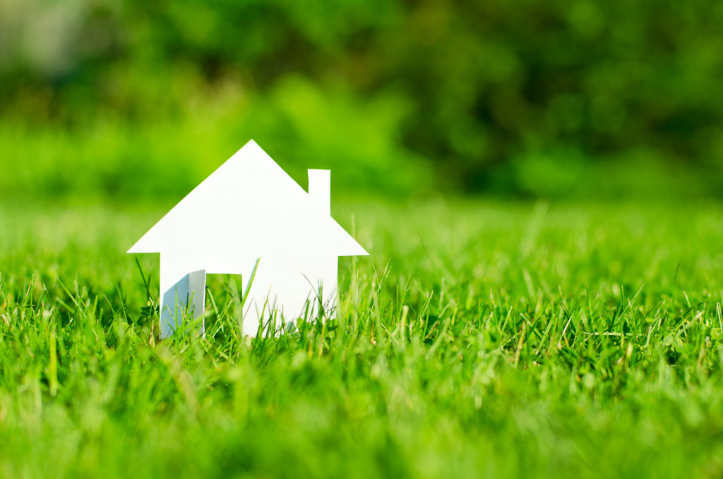 miniature paper house in a field of green grass