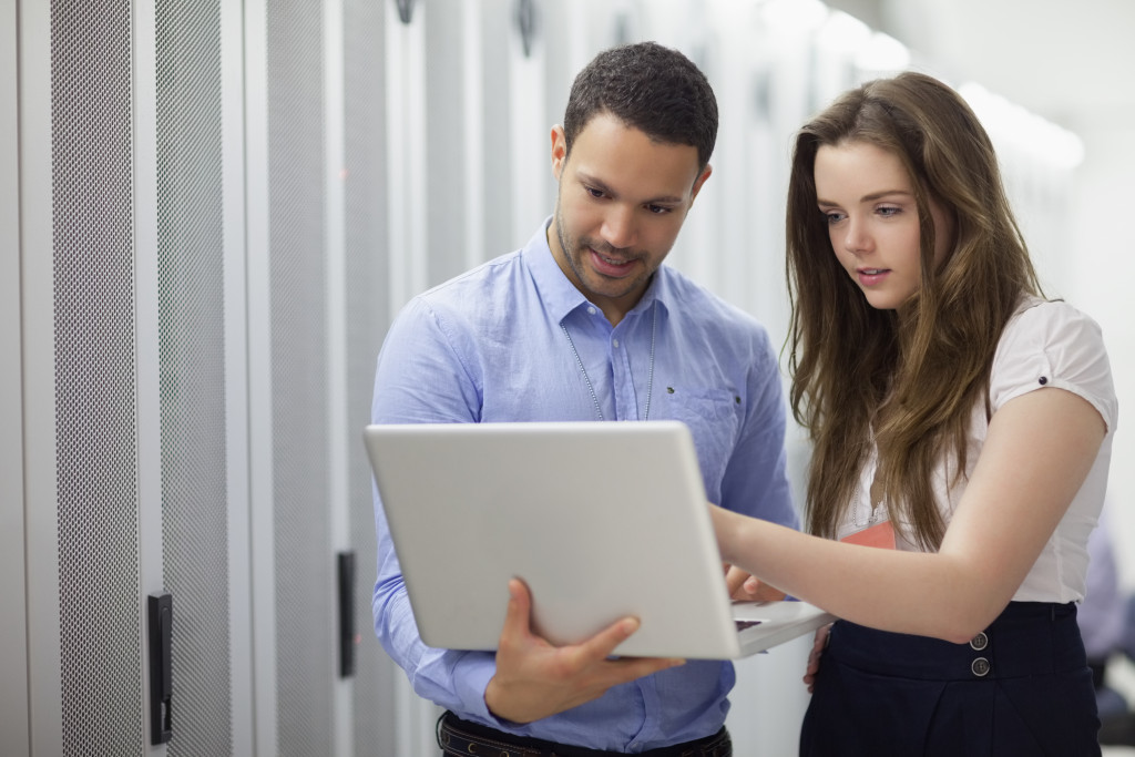 man holding a laptop while woman discussing