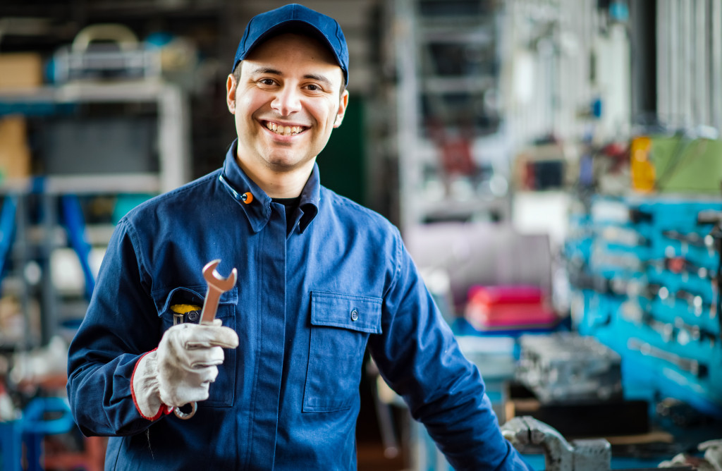 a mechanic smiling while holding a tool