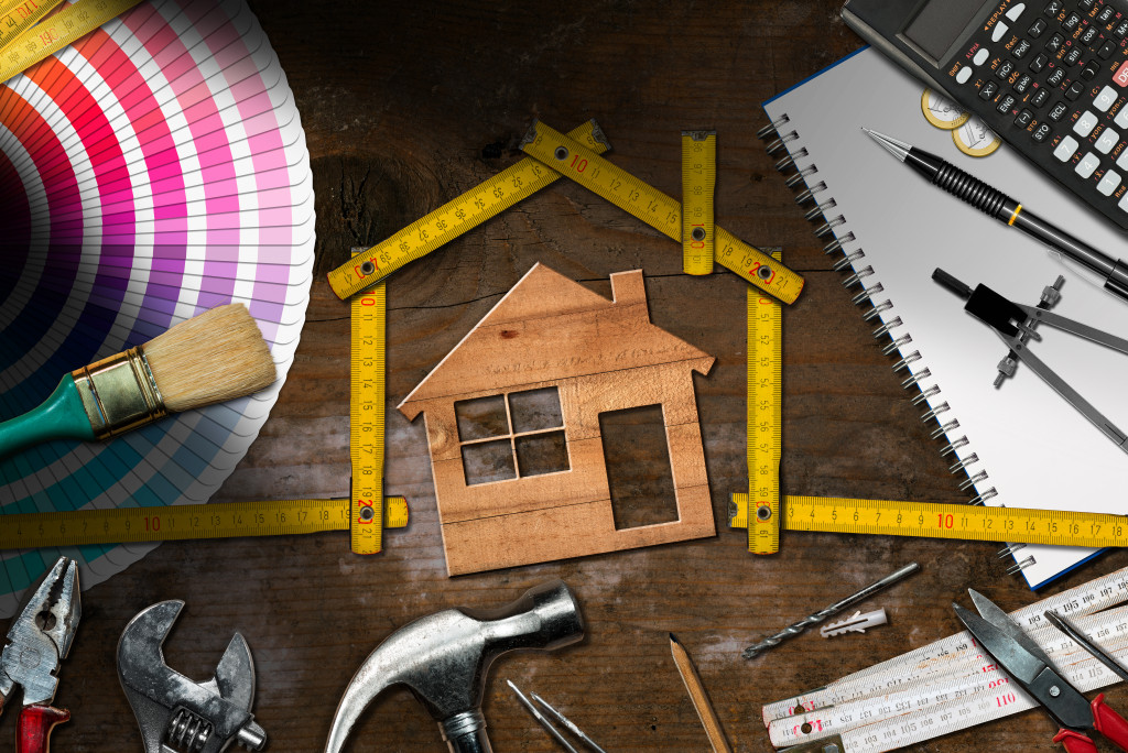 home maintenance with wooden home in the middle and tools around it