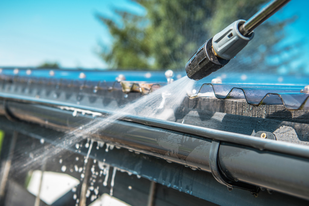 Someone using a power washer to clean metal gutters