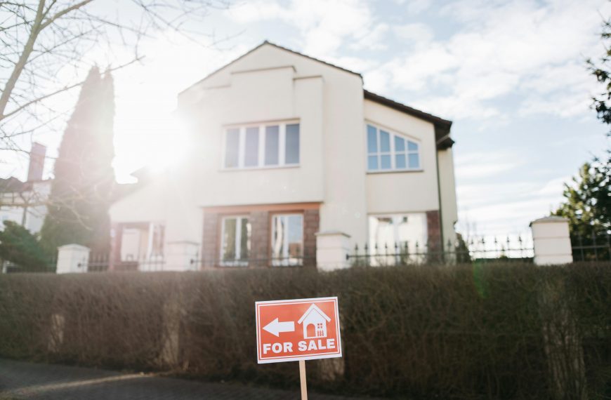 two-story home with a 'For Sale' sign in the front yard