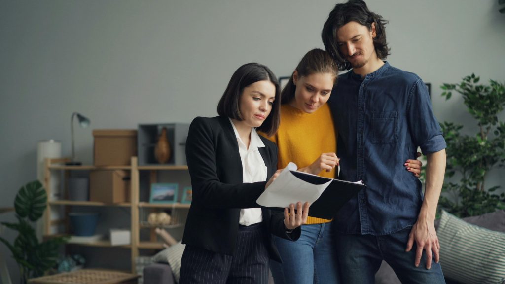 home appraiser and a couple reviewing paperwork on a clipboard