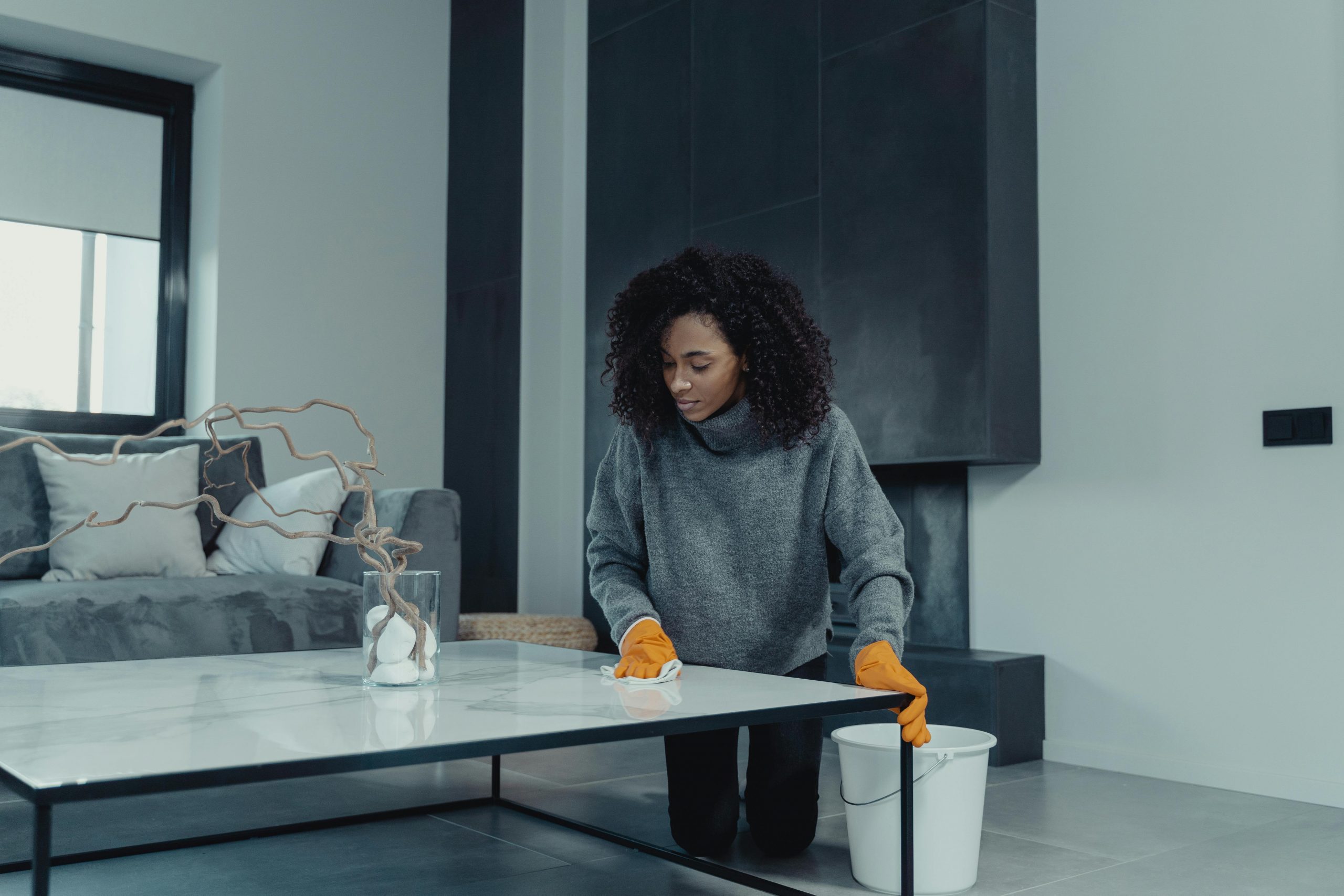 woman wiping down a coffee table in a modern living room